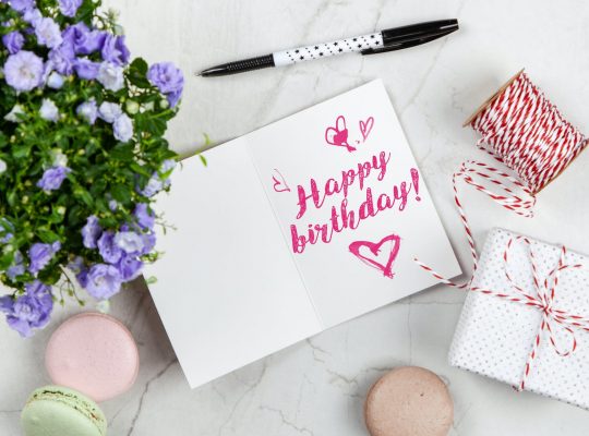 happy birthday card beside flower thread box and macaroons